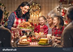 a group of people sitting around a table with food and candles in front of them