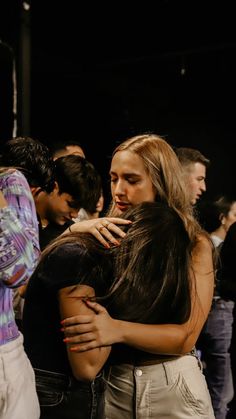 two women hugging each other in front of a crowd