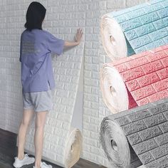 a person standing next to a wall covered in rolls of paper