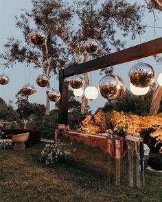 an outdoor area with hanging lights and flowers in the foreground, surrounded by trees