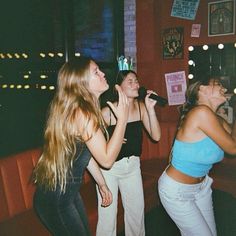 three young women singing into microphones in a bar