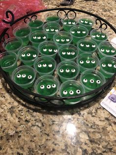 a bowl filled with green plastic cups covered in googly eyes on top of a counter