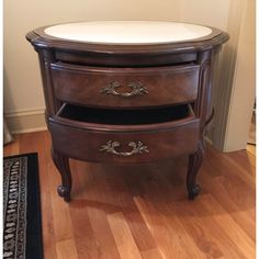 a wooden table with two drawers and a mirror on it's side, in front of a door