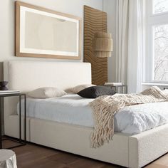 a white bed sitting in a bedroom next to a window