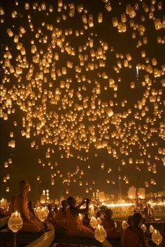 people are sitting on the ground and floating lanterns in the sky with words happy birthday