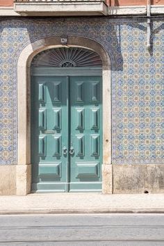 a green door is in front of a blue and white wall with an arched doorway