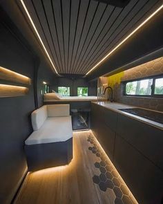 the interior of a modern house with wood flooring and white furniture, along with lights on the ceiling