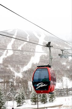 a red ski lift going up the side of a snow covered mountain