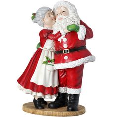 a figurine of santa and mrs claus kissing each other on a wooden base