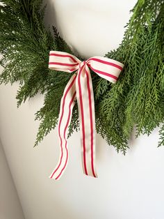 a christmas wreath with red and white striped ribbon