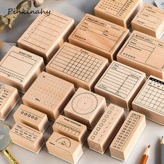 many wooden stamps are arranged on a table with some pencils and other items nearby