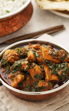 a bowl filled with chicken and spinach next to rice on top of a table