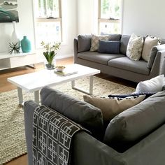 a living room with two couches, a coffee table and some pillows on the floor