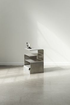 a white table sitting in the middle of a room next to a wall with two birds on it