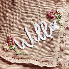 an embroidered name on a sweater with crochet lace and flowers around the letters