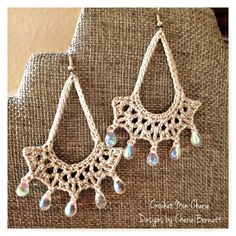 crocheted earrings with tear drops and beads on the end are hanging from a piece of fabric