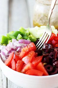 a white bowl filled with lots of different types of food and a fork in it