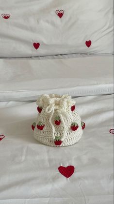 a white crocheted purse sitting on top of a bed next to a pillow