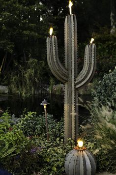 a large cactus plant with two lights on it's side in the middle of a garden