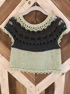 a crocheted top hanging on a wooden wall