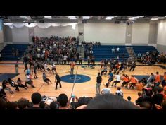 a group of people standing on top of a basketball court in front of an audience