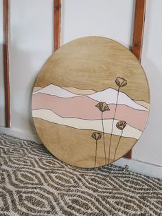 a wooden plate sitting on top of a carpeted floor next to a wall with flowers painted on it