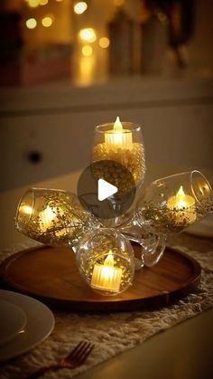 candles are lit on a wooden plate with glass cups and saucers in the center