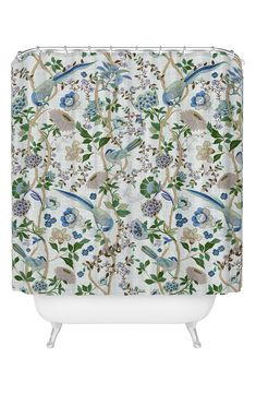 a white shower curtain with blue and green flowers on the outside, and a bird in the middle