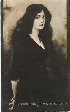 an old black and white photo of a woman with long hair wearing a dark dress