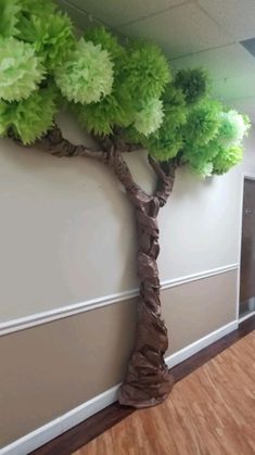 a tree made out of tissue paper sitting on top of a wooden floor next to a wall