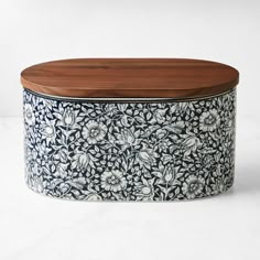 a blue and white box with wooden lid on a white tablecloth covered surface in the shape of a flower pattern