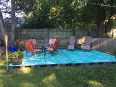 a patio with chairs and a table in the middle of it, surrounded by grass