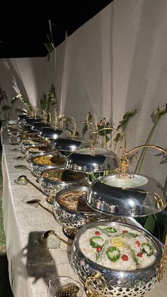 a long table filled with lots of different types of food on top of metal pans