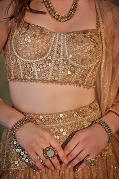 a close up of a woman wearing a gold outfit and jewelry on her hands,