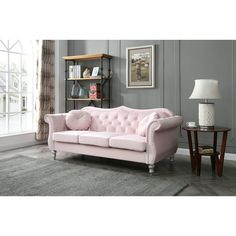 a pink couch sitting on top of a rug in a living room next to a window