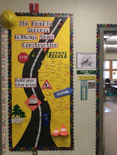 a bulletin board on the wall in a school hallway with construction signs and other decorations