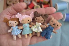 a hand is holding five little felt dolls