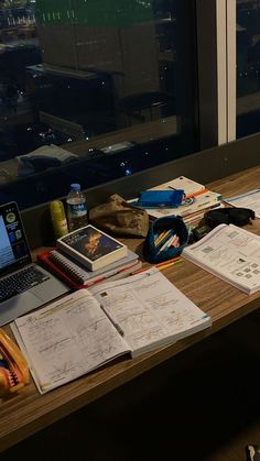 a laptop computer sitting on top of a wooden desk next to papers and pencils