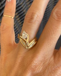 a woman's hand with two gold rings on top of her finger and the ring has three diamonds in it