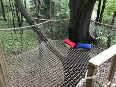 a hammock in the woods with two pillows on it