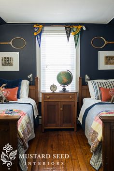 two beds in a room with blue walls and wooden floors, one has a globe on top of the headboard