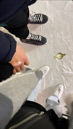 two people standing next to each other on top of a snow covered ground with their feet in the air