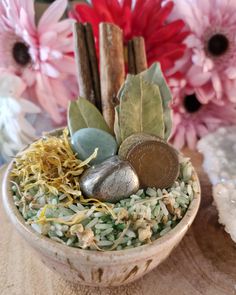 a small bowl filled with lots of different types of rocks and plants next to flowers