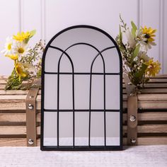 an arched window sitting on top of a wooden table next to flowers and vases