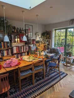 a dining room table and chairs in front of a large book shelf filled with books