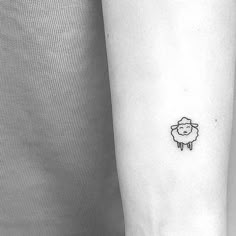 a small sheep tattoo on the left inner forearm and wristband is shown in this black and white photo