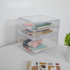 a clear plastic box with three compartments on top of it next to a notebook and pen