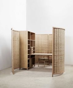 a room divider made out of wicker with a table and chair in it