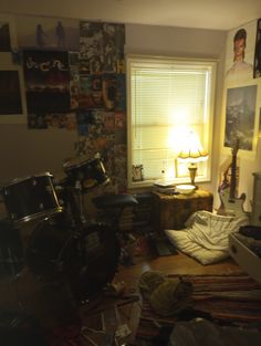 a bedroom with a drum set and various pictures on the wall behind it in front of a window