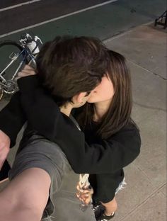 a man and woman sitting next to each other on the ground with bikes in the background